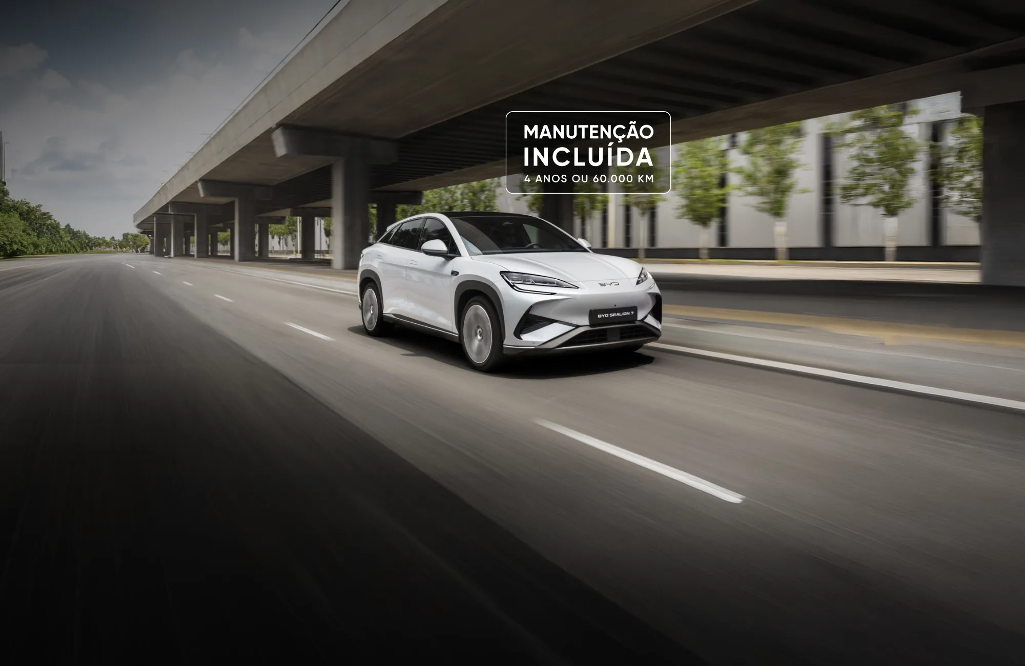Imagem publicitária do BYD Sealion 7 branco em movimento com o texto "Manutenção Incluída – 4 anos ou 60.000 km".