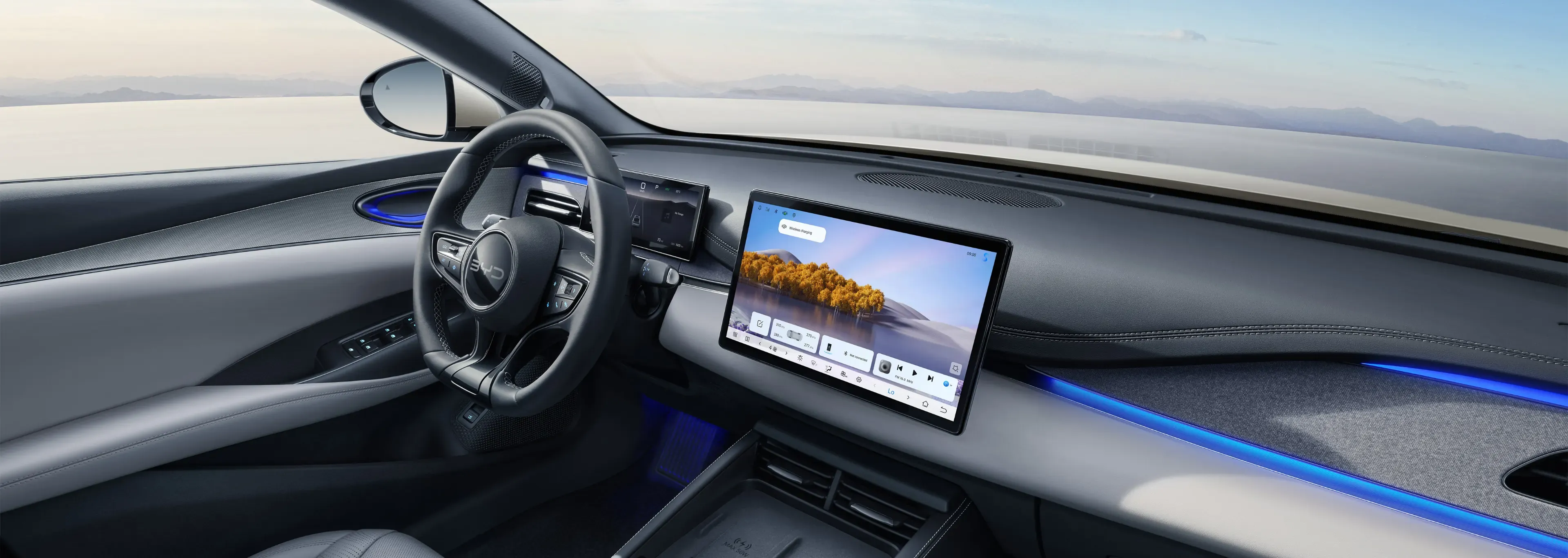 "Habitáculo do BYD SEAL 6 com ecrã multimédia flutuante, volante em pele com logótipo BYD e consola central moderna."
