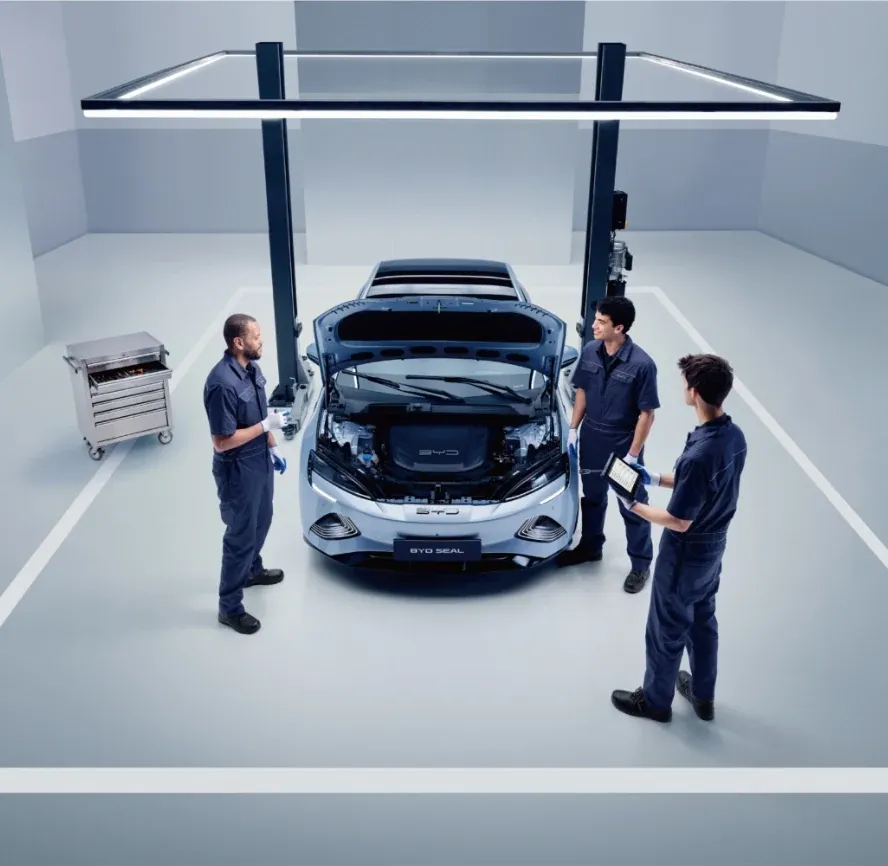 Três técnicos da BYD Service conversam ao pé de um BYD com o capot aberto