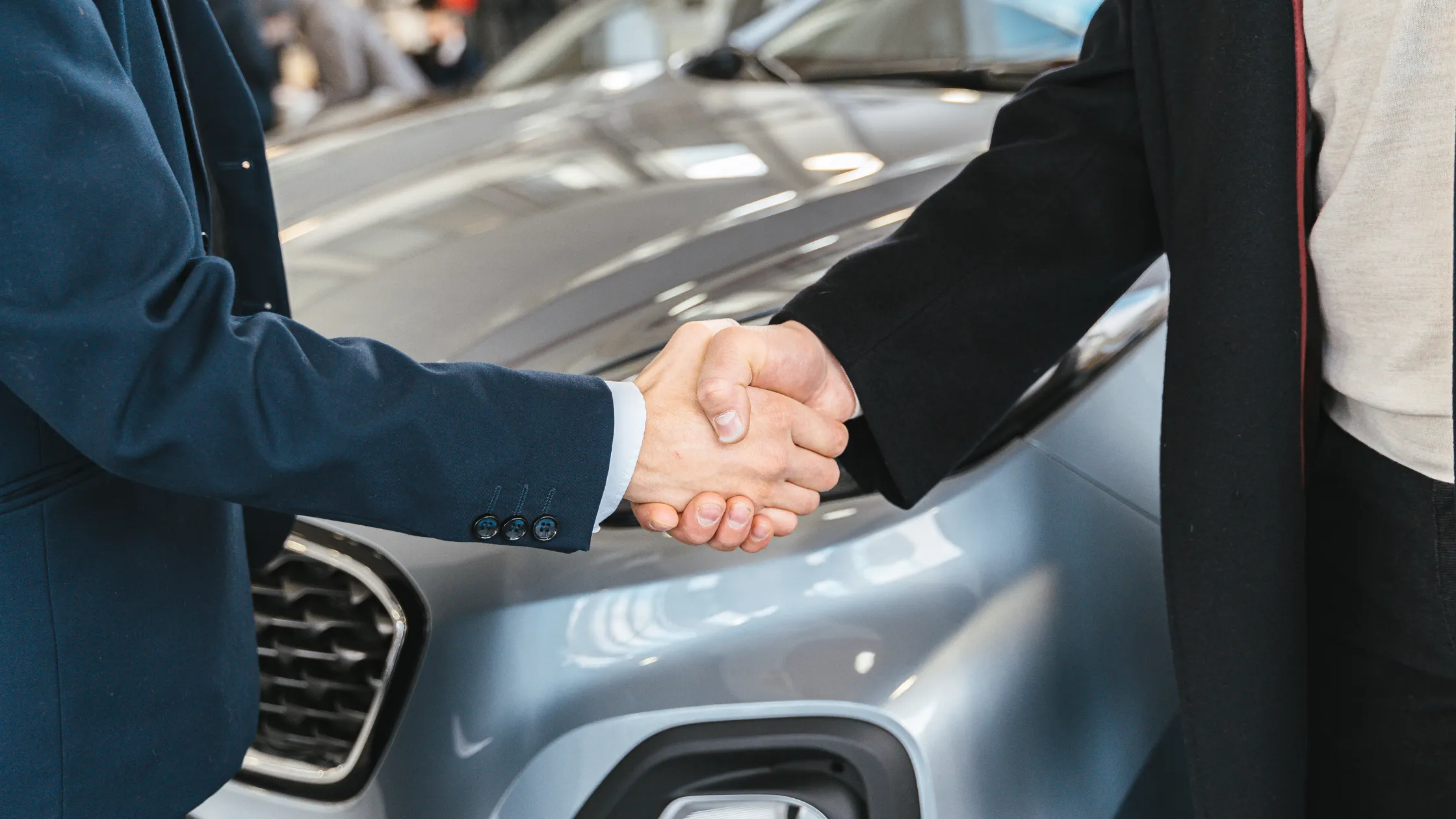 Comprador y vendedor entrelazan las manos al cerrar la compra de un coche de segunda mano.