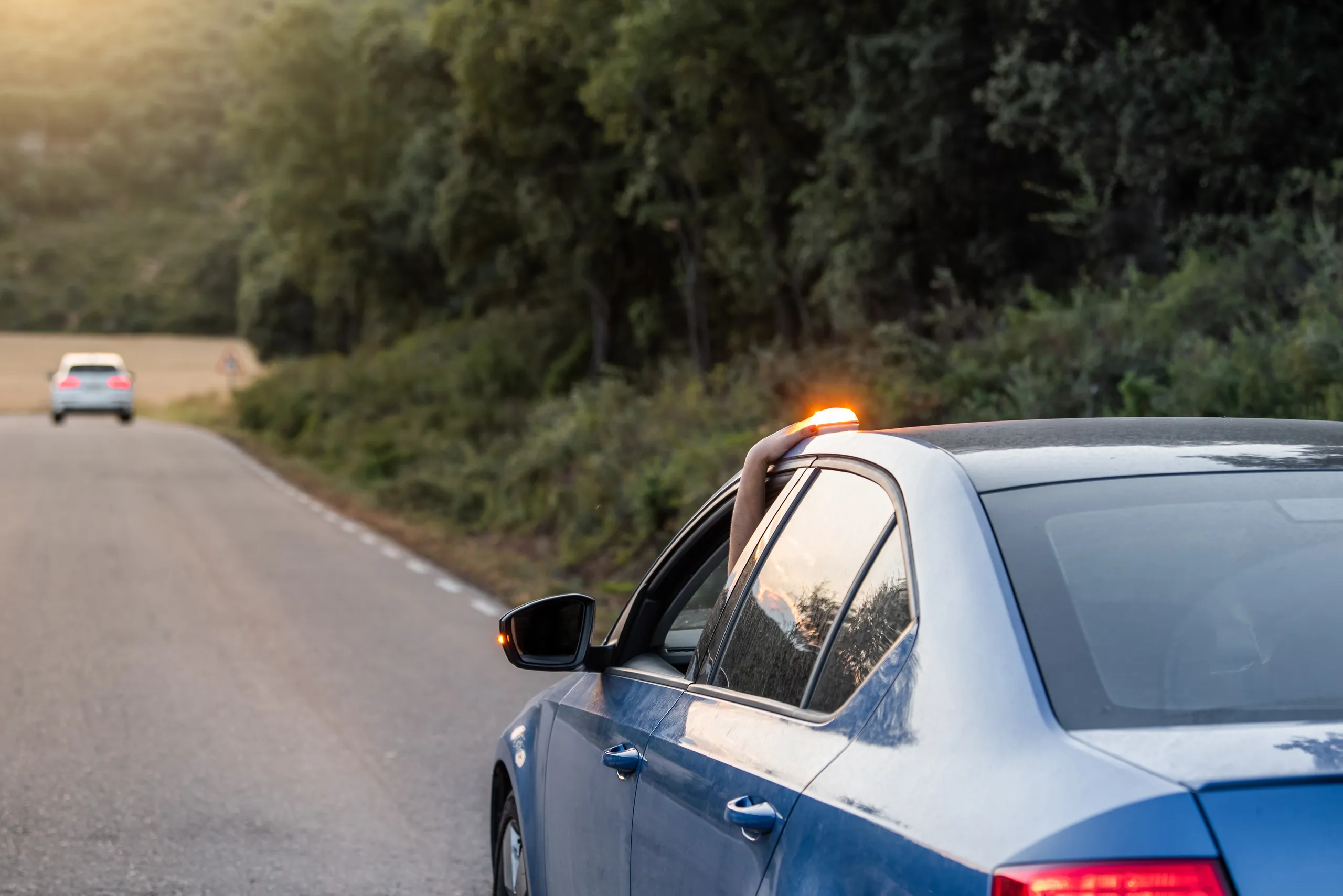 Coche en carretera con señalización V16, mostrando cómo usarla debidamente en emergencias.