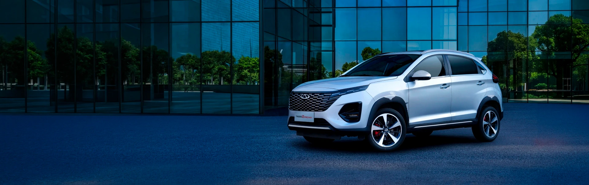 Chery Tiggo 2 branco em destaque estacionado frente a edifício moderno com fachada de vidro