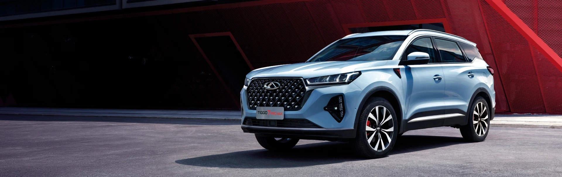 Primeiro plano da grelha frontal de um Chery Tiggo 7 azul claro sob luz solar.