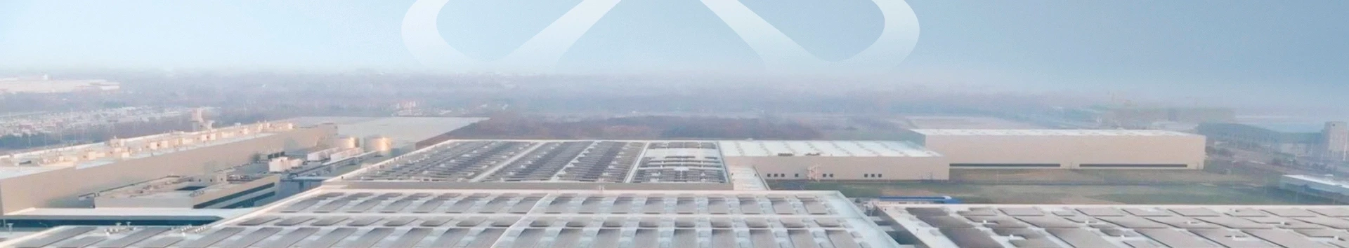 Vista aérea de um grande stand de automóveis e centro logístico sob um céu limpo.