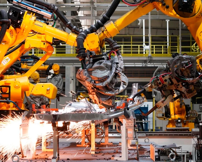 Industrial robotic arms performing high-precision automated welding on a vehicle production line in a modern manufacturing plant