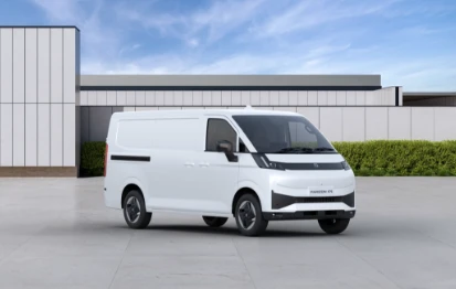 Carrinha comercial branca Farizon V7E, com tejadilho standard, estacionada num pátio plano exterior com um edifício moderno e vegetação ao fundo. 