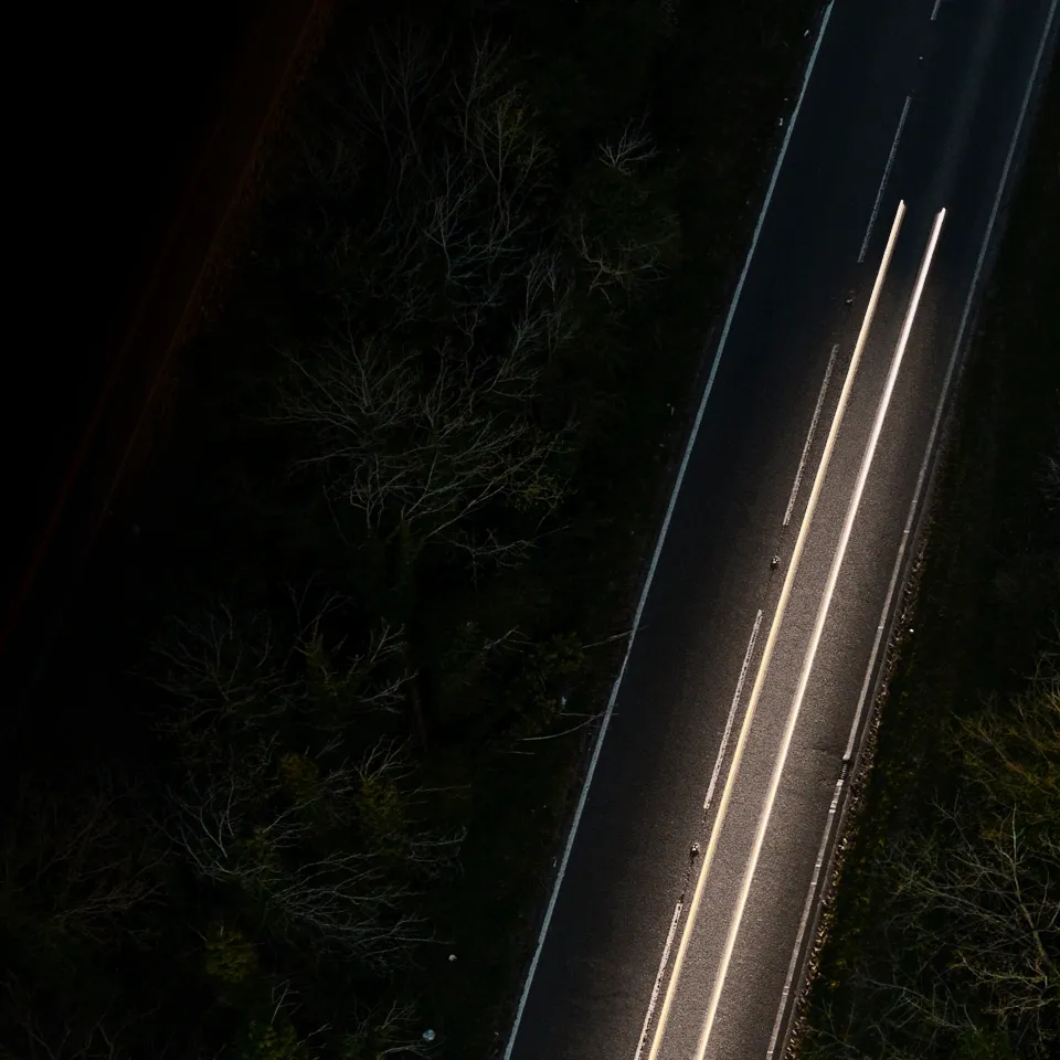 vista aérea noturna de uma estrada com rastos de faróis de um automóvel