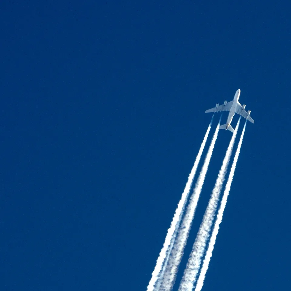 avião comercial a voar com rasto de fumo branco