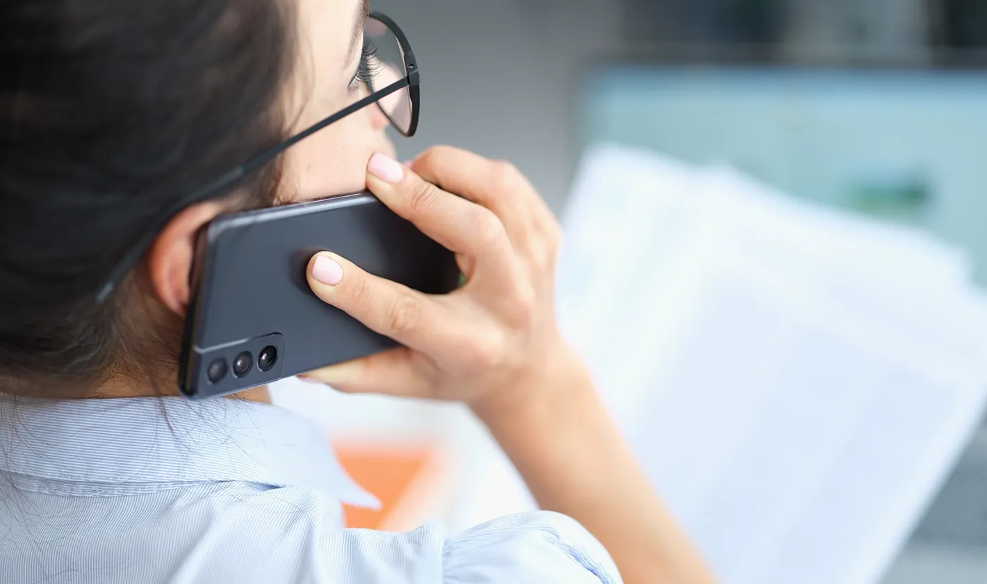 mulher em chamada no smartphone enquanto lê documento