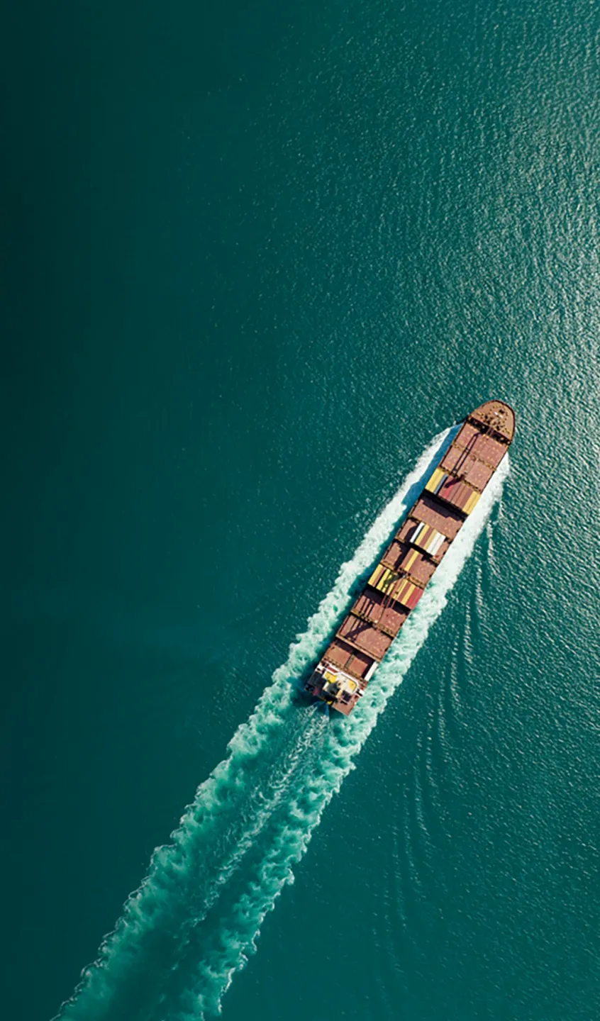 vista aérea de um navio com contentores no mar com águas verde-azuladas.