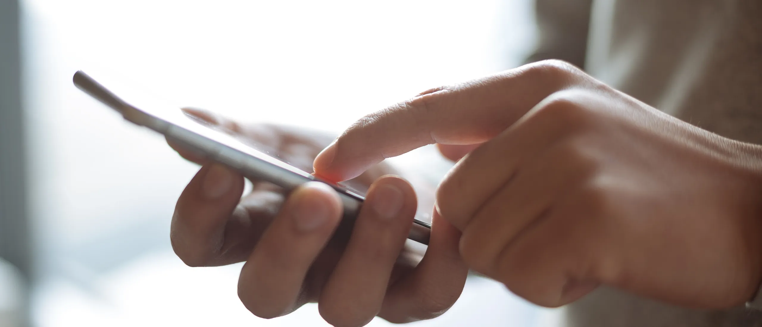 mão a segurar num smartphone e outra mão a interagir com o ecrã