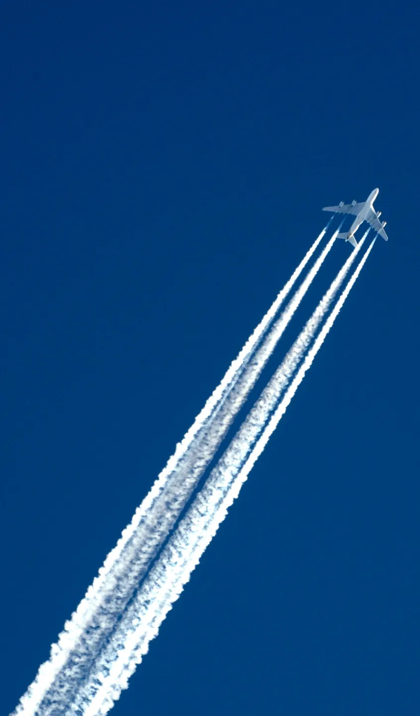 avião comercial a voar com rasto de fumo branco