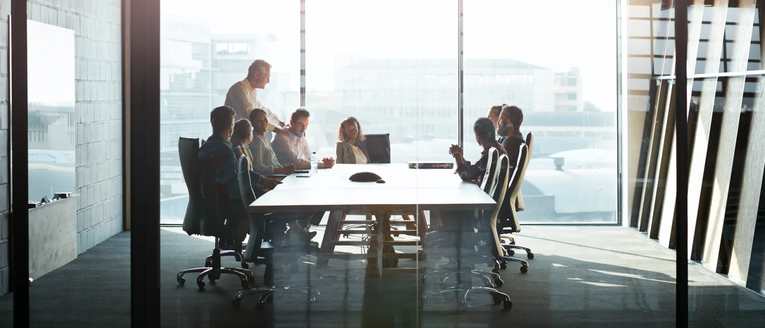 9 pessoas descontraídas e reunidas à volta de uma mesa de trabalho