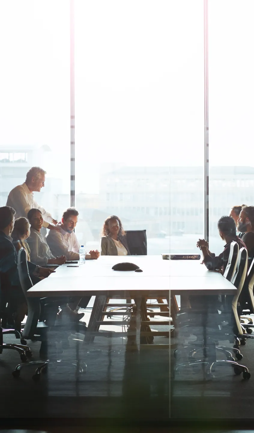 9 pessoas descontraídas e reunidas à volta de uma mesa de trabalho
