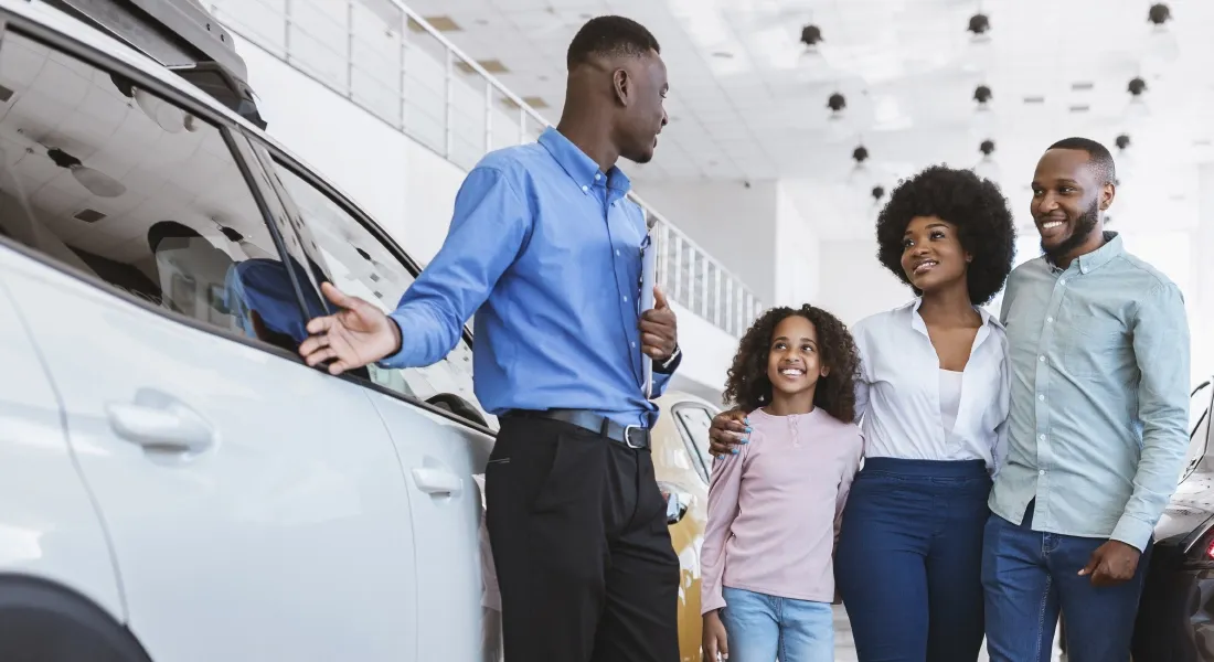 Vendeur présentant une voiture à une famille