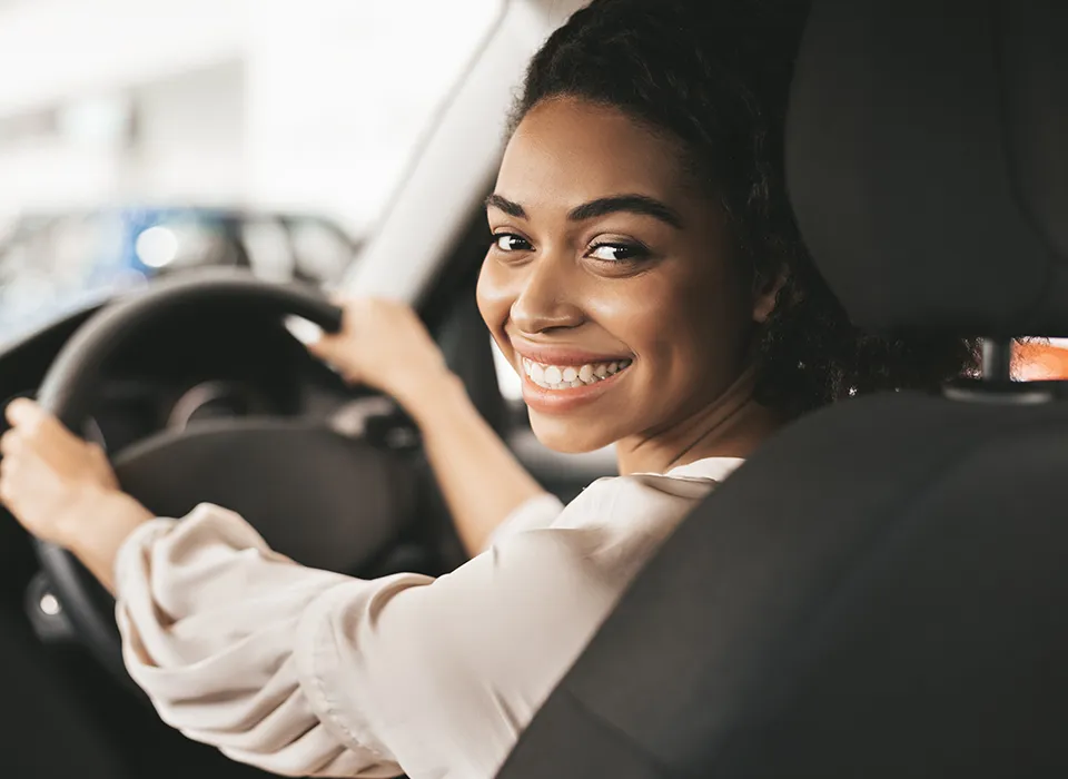 Personne souriante au volant de son véhicule JMC