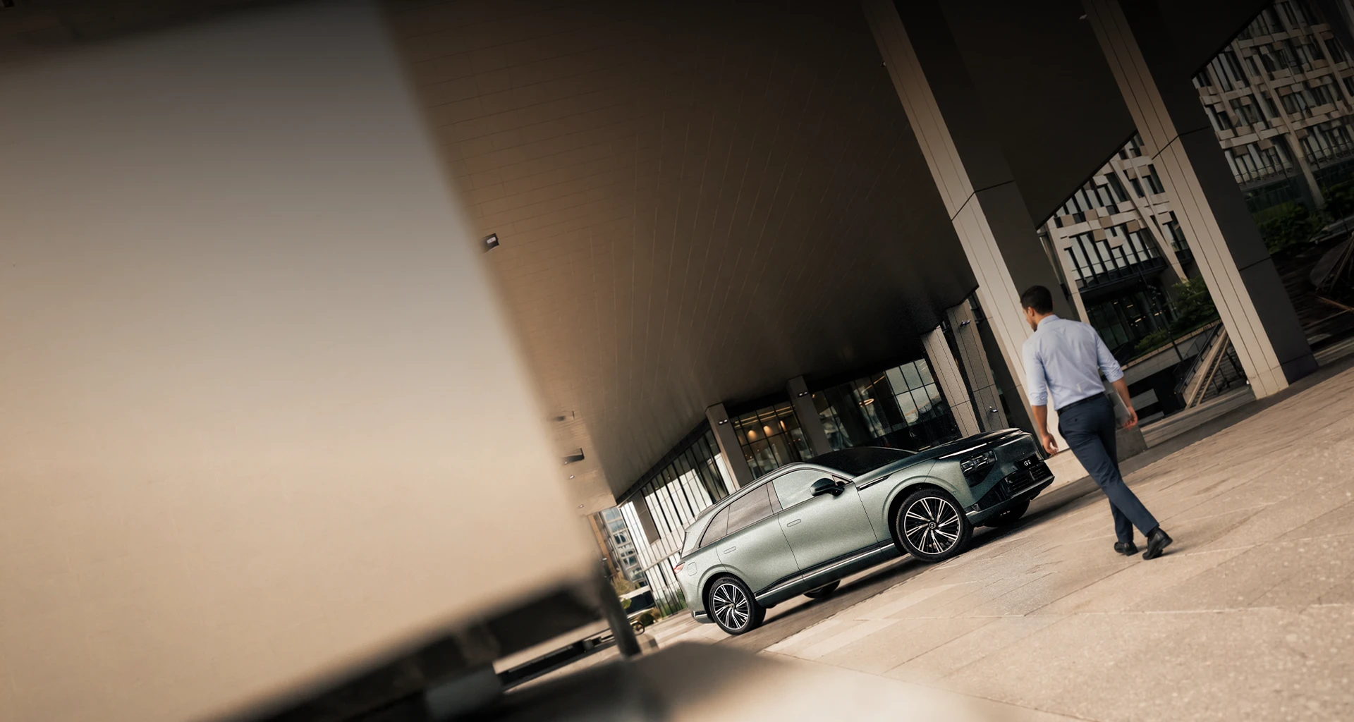 Empresário aproxima-se do SUV elétrico XPENG G9 junto a edifício moderno. 