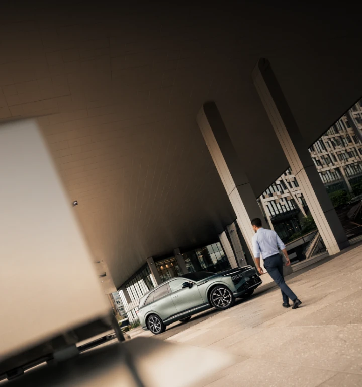Empresário aproxima-se do SUV elétrico XPENG G9 junto a edifício moderno. 